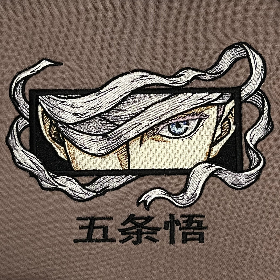 Hoodie brodé Eyes Satoru Gojo Kaito Global — gros plan du motif sur textile.