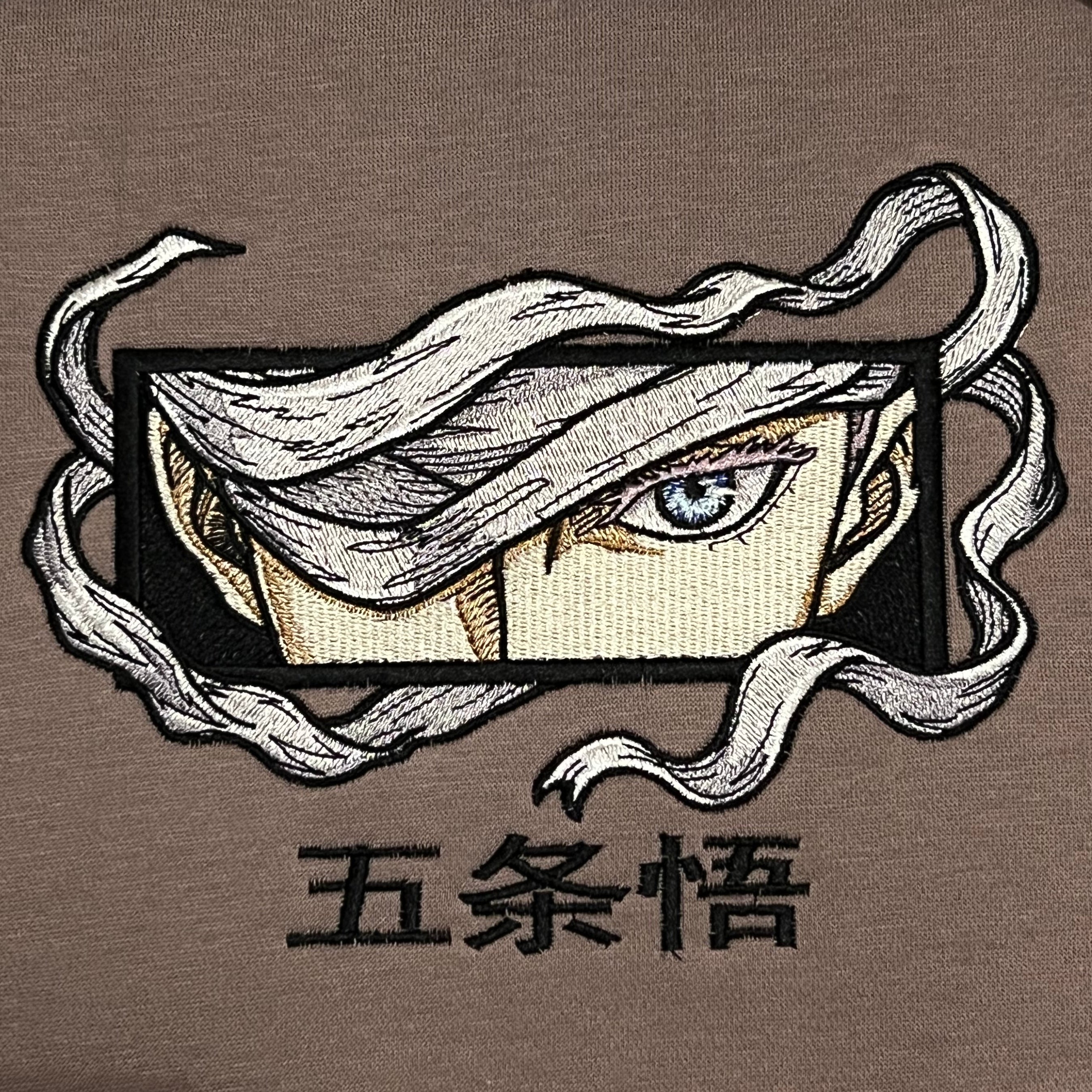 Hoodie brodé Eyes Satoru Gojo Kaito Global — gros plan du motif sur textile.