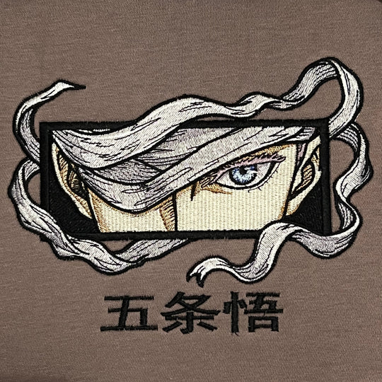 Hoodie brodé Eyes Satoru Gojo Kaito Global — gros plan du motif sur textile.